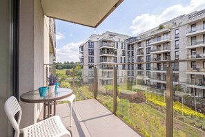 A balcony with a table and chairs, overlooking a residential building complex. - Cozy Studio Near the Wisla River | Balcony | Zabłocie (Kraków)