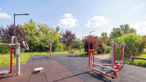 Fitnessgeräte im Freien in einem Park mit befestigtem Weg.