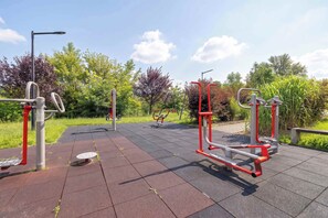 Outdoor exercise equipment in a park with a paved walkway. - Cozy Studio Near the Wisla River | Balcony | Zabłocie (Kraków)