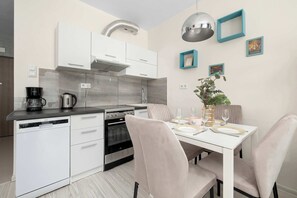 A modern kitchen with white cabinetry, a built-in oven, and a coffee maker. - Cozy Studio Near the Wisla River | Balcony | Zabłocie (Kraków)