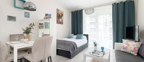Una habitación moderna y luminosa con cama, comedor y zona de estar.