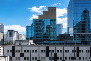 A modern high-rise building with reflective glass windows, surrounded by other buildings. - Spacious Apartment with Balcony | Workspace | Close to the Center (Warszawa)