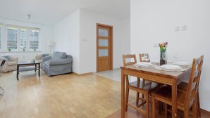 Ein modernes Wohnzimmer mit Essbereich, Holzmöbeln und Blick durch ein großes Fenster.