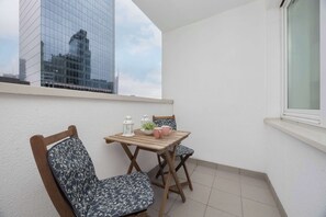A small balcony with a wooden table and two chairs, a potted plant, and two white lanterns. - Spacious Apartment with Balcony | Workspace | Close to the Center (Warszawa)