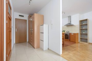 A modern kitchen with wooden cabinets, a white refrigerator, and a built-in oven. - Spacious Apartment with Balcony | Workspace | Close to the Center (Warszawa)