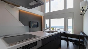 Una cocina moderna con estufa integrada, un lavamanos y una banqueta.
