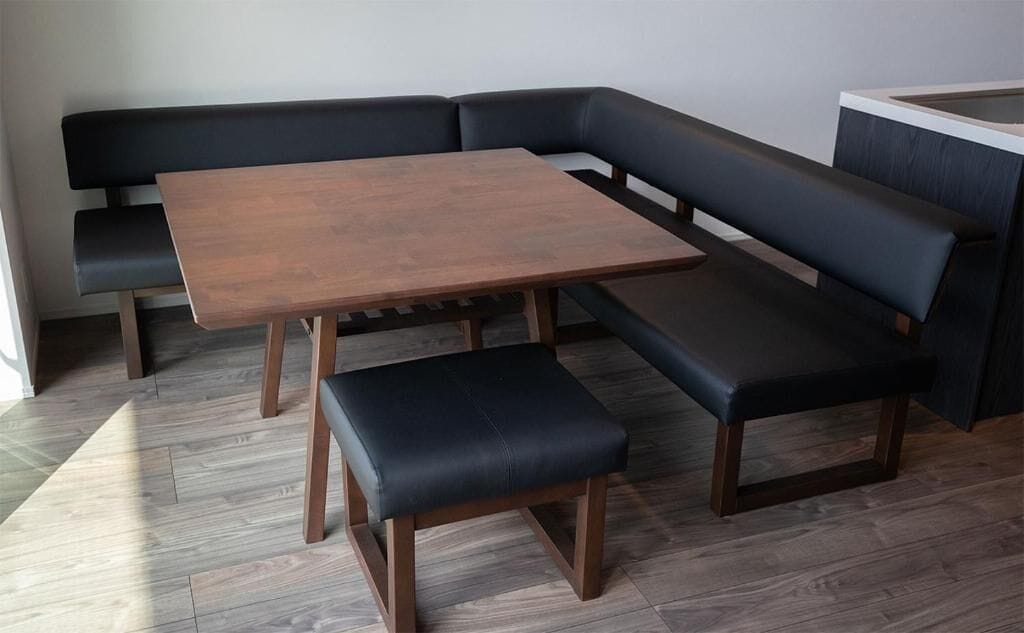 Eine Sitzecke mit Holztablett und zwei schwarzen Sitzbänken.