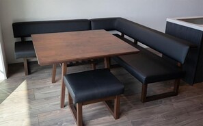 A corner seating area with a wooden table and two black cushioned benches. - Tabinoteitaku Y-beach (yunohama,Tauruoka)