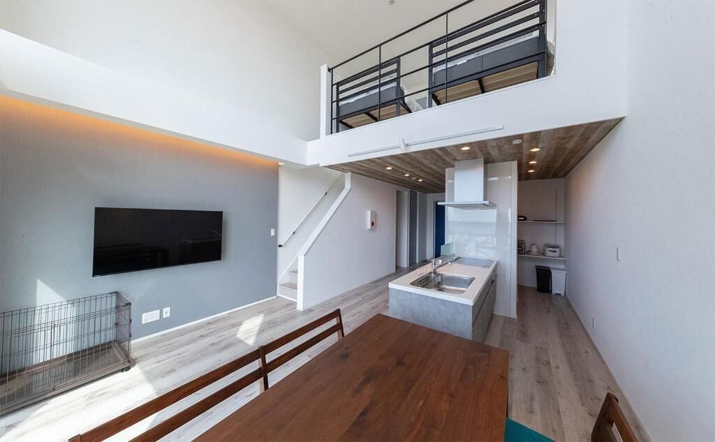 A modern interior with a dining area, kitchen, and a staircase leading to a loft.