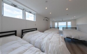 Una habitación con tres camas, ventanas amplias y vista al mar.