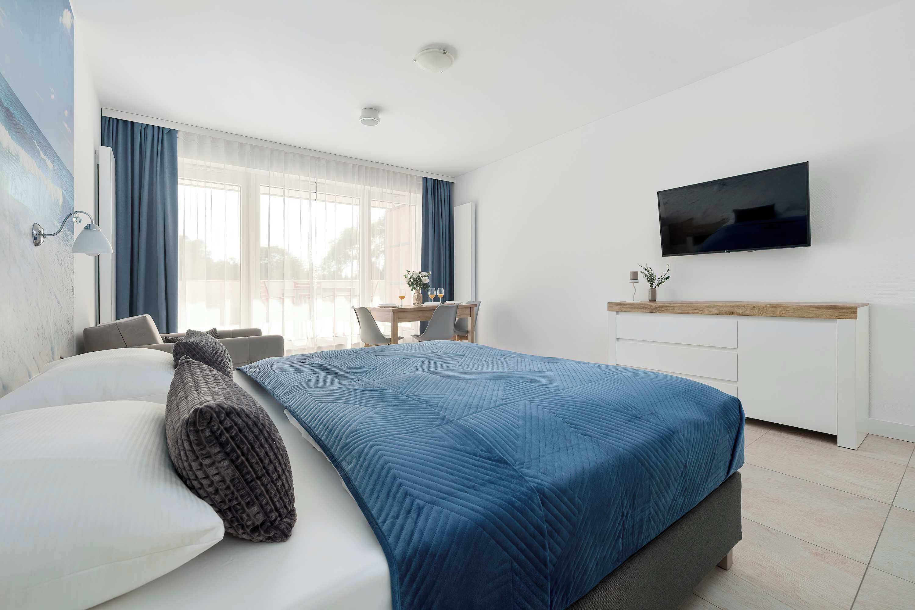 Ein modernes Schlafzimmer mit einem Bett, einem Schreibtisch und einem Fernseher.