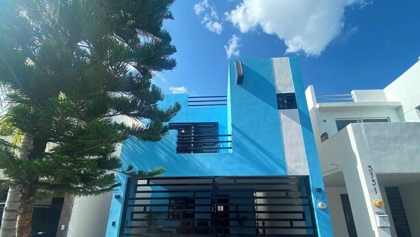 Un bâtiment moderne à la façade bleue, doté d’une entrée sécurisée par un portail et d’une enseigne indiquant clairement l’adresse.