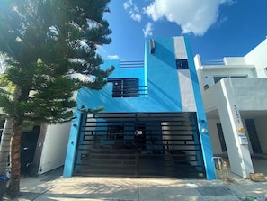 A modern building with a blue facade, a gated entrance, and a visible address sign.