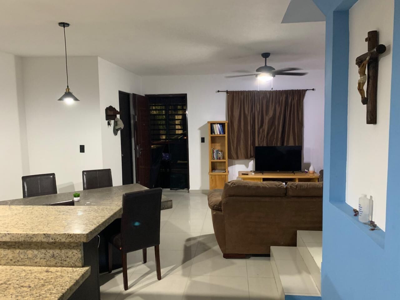 A living room with a television, sofa, and a dining area with chairs and a table.