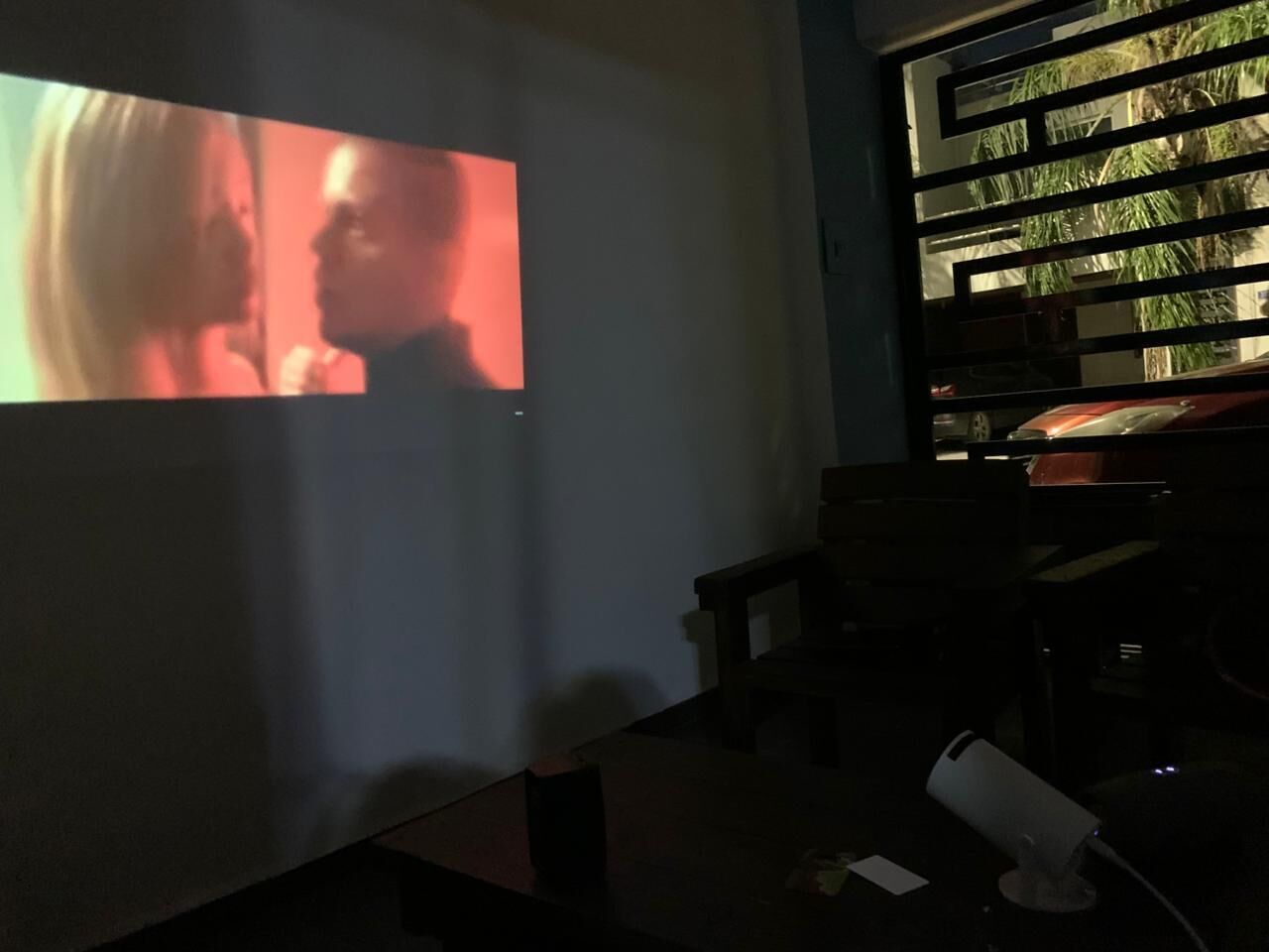 Een projectiescherm in een kamer met weinig licht, met een boekenplank op de achtergrond.
