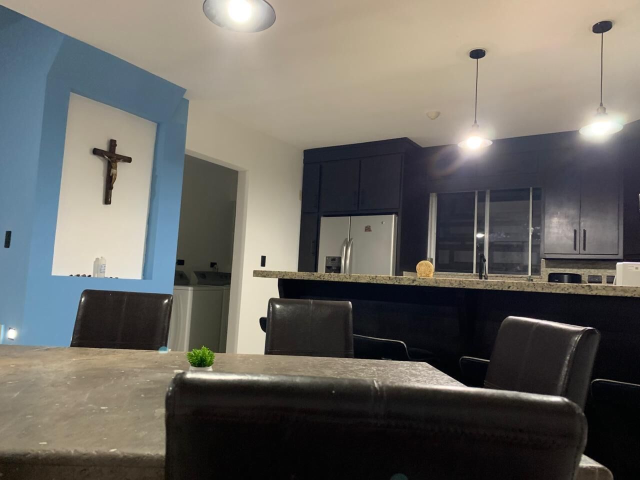 A modern kitchen with dark cabinetry, a granite countertop, and a cross on the wall.
