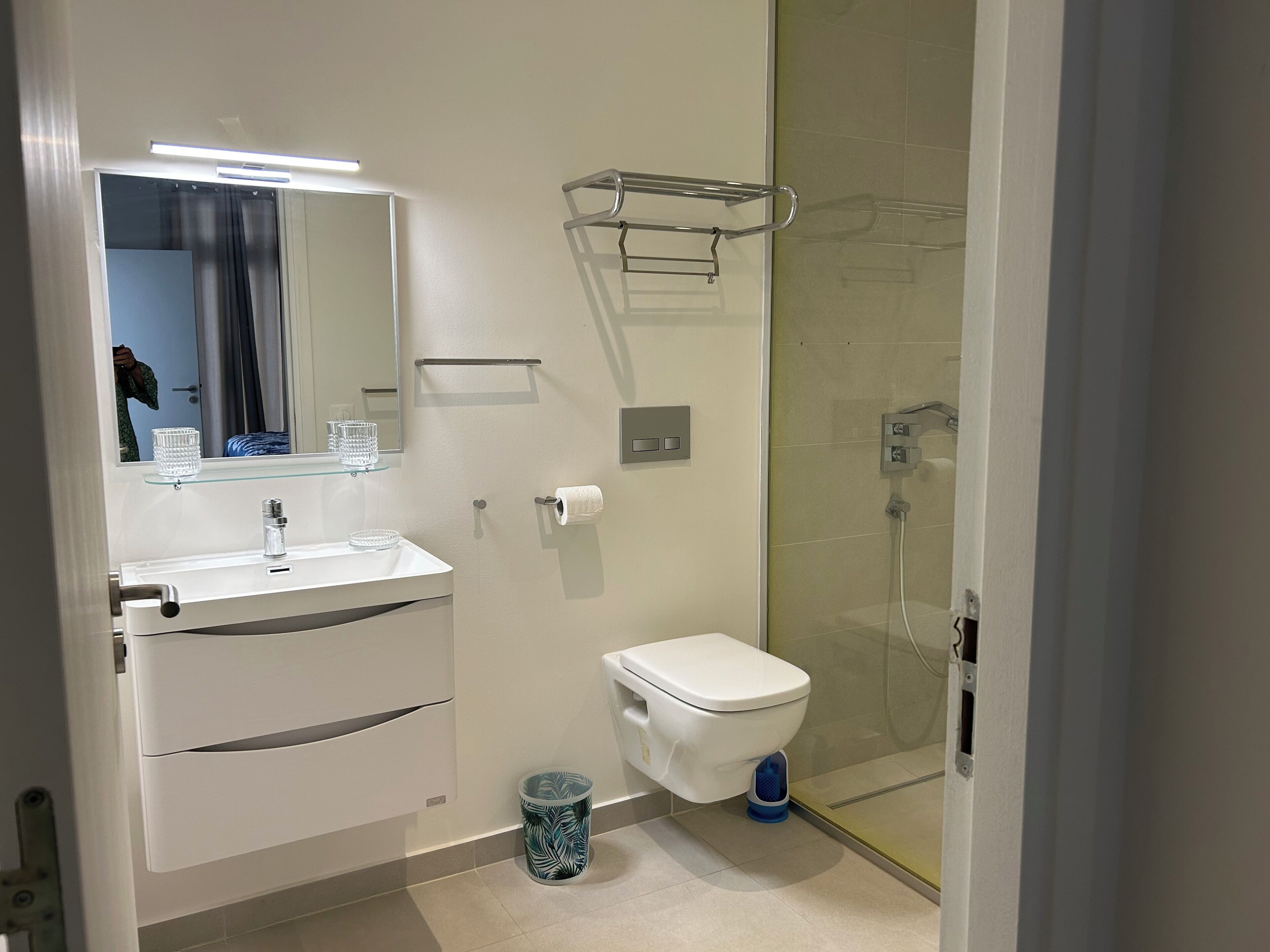Une salle de bain moderne avec un lavabo, un miroir et des toilettes, le tout de couleur blanche.