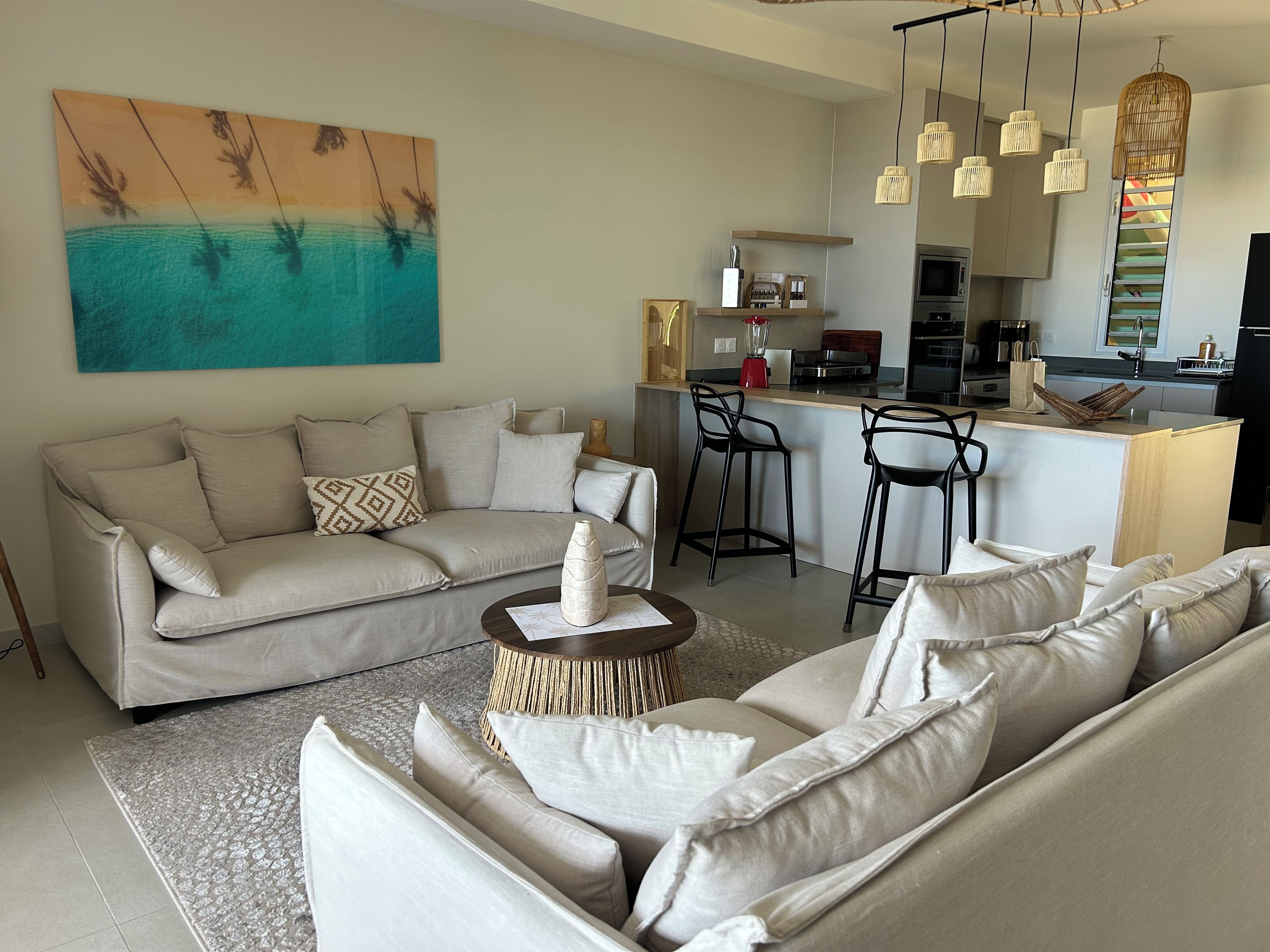 A modern living room with a sofa, a coffee table, and a kitchen area with a bar.