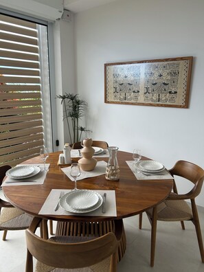 A dining area with a round wooden table set for four, white plates, glasses, and a woven centerpiece.