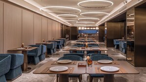 A modern restaurant with multiple dining tables, blue upholstered chairs, and a central walkway. - Crystal Orange Tianjin Eye Ancient Culture Street (Tianjin)
