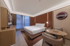 Una camera d'albergo con un letto, un comodino, una sedia e una televisione.