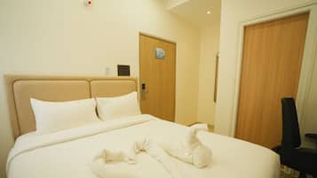 Une chambre d’hôtel avec un lit, un peignoir, une chaise et une porte sur laquelle est apposée une pancarte « Il est interdit de fumer ».