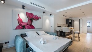 Ett modernt hotellrum med en stor säng, en matplats och ett kök.