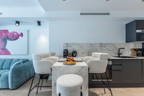 A modern kitchen with a marble countertop, a dining table with chairs, and a coffee machine. - Renovated 1BR | Steps from Croisette & Beach (Cannes)