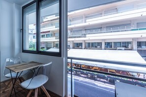 A balcony with a table and chairs, overlooking a building with multiple floors and balconies. - Renovated 1BR | Steps from Croisette & Beach (Cannes)