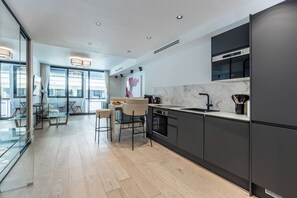 A modern kitchen with a marble backsplash, a built-in oven, and a large window overlooking a cityscape. - Renovated 1BR | Steps from Croisette & Beach (Cannes)