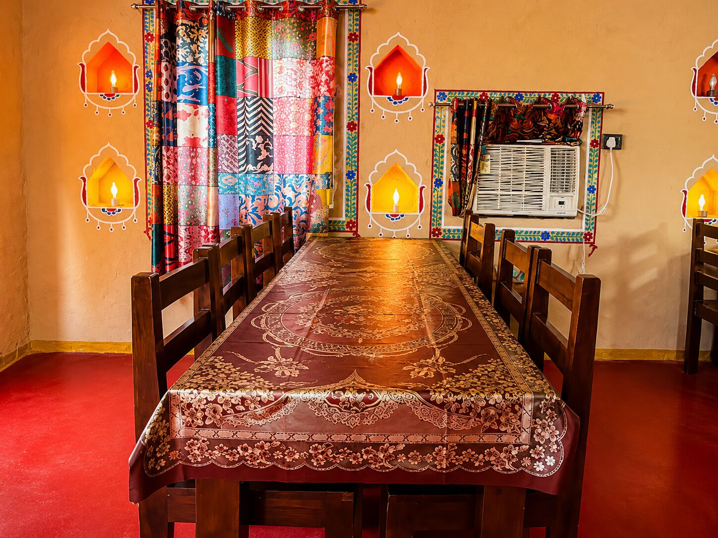 Un espace repas avec une longue table, des chaises et des rideaux à motifs.