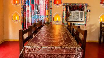 Un espace repas avec une longue table, des chaises et des rideaux à motifs.