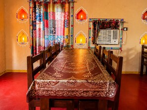 Een eetgedeelte met een lange tafel, stoelen en gordijnen met een patroon.
