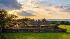 Paisaje rural con casas tradicionales de techo de paja, un muro de piedra y un campo cubierto de hierba.