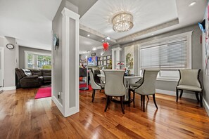 A spacious living area with a dining table, chairs, and a modern chandelier. - Lovely 4-bedroom house in Vancouver- Walk 9 Mins SkyTrain & Near YVR (Vancouver)