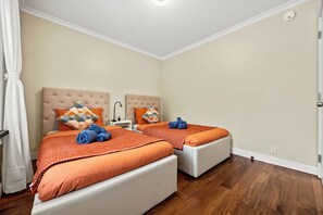 A hotel room with two beds, a white door, and a wooden floor. - Lovely 4-bedroom house in Vancouver- Walk 9 Mins SkyTrain & Near YVR (Vancouver)