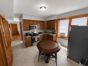 A compact kitchen with wooden cabinets, a stainless steel stove, a microwave, and a refrigerator.