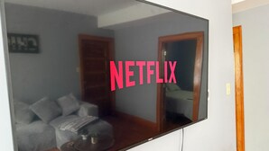 Ein an der Wand befestigter Fernseher, auf dessen Bildschirm 'NETFLIX' angezeigt wird.