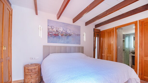 Un dormitorio con una cama grande, un armario de madera y un cuadro en la pared.