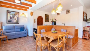 Una sala de estar acogedora con un sofá azul, una mesa de comedor de madera y sillas de mimbre.