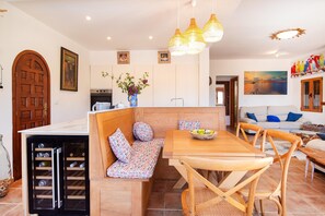 A cozy kitchen with a wooden bench, a dining table, and a wine cooler.
