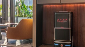 A modern hotel lobby with a robot, a wooden wall, and a seating area. -  IntercityHotel Tianjin Binhai Yujiapu Financial District (Tianjin)