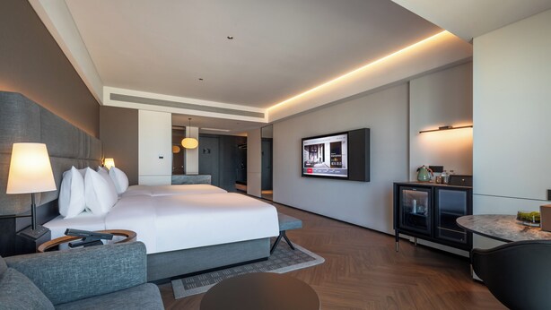 A modern hotel room with a large bed, a sofa, a desk, and a television. -  IntercityHotel Tianjin Binhai Yujiapu Financial District (Tianjin)