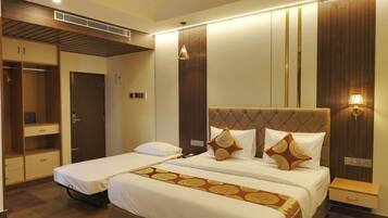A hotel room with two single beds, a wardrobe, a bedside table with a lamp, and a built-in heater.