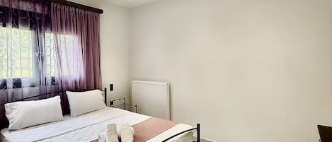 Une chambre à coucher moderne avec un lit, un radiateur et une fenêtre avec des rideaux.
