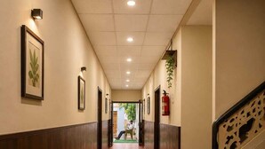 Ein Hotel-Flur mit Holzboden, gerahmten Kunstwerken an den Wänden und einer Treppe mit dekorativer Geländer.