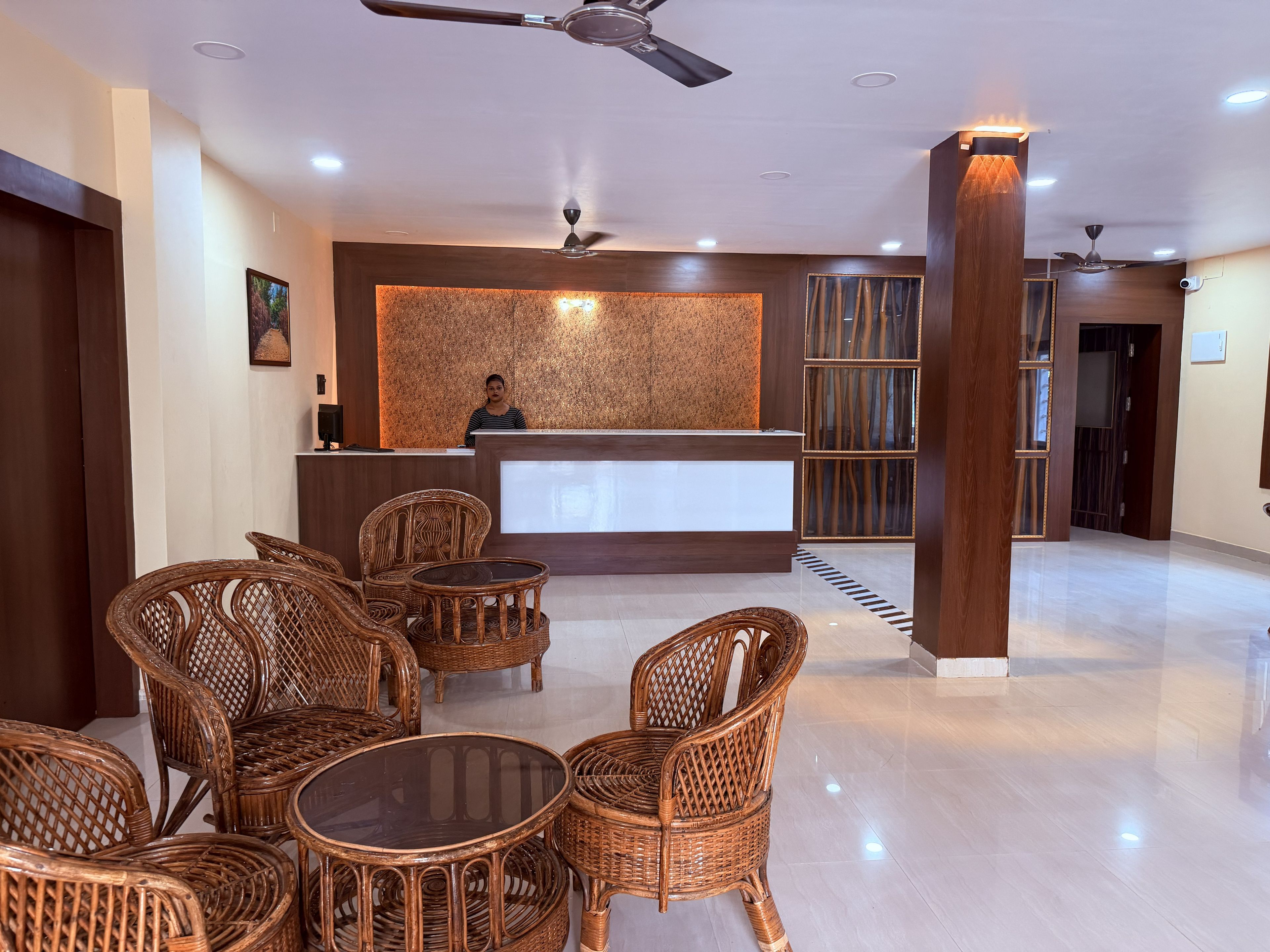 A hotel reception area with a receptionist, wicker furniture, and a modern design.