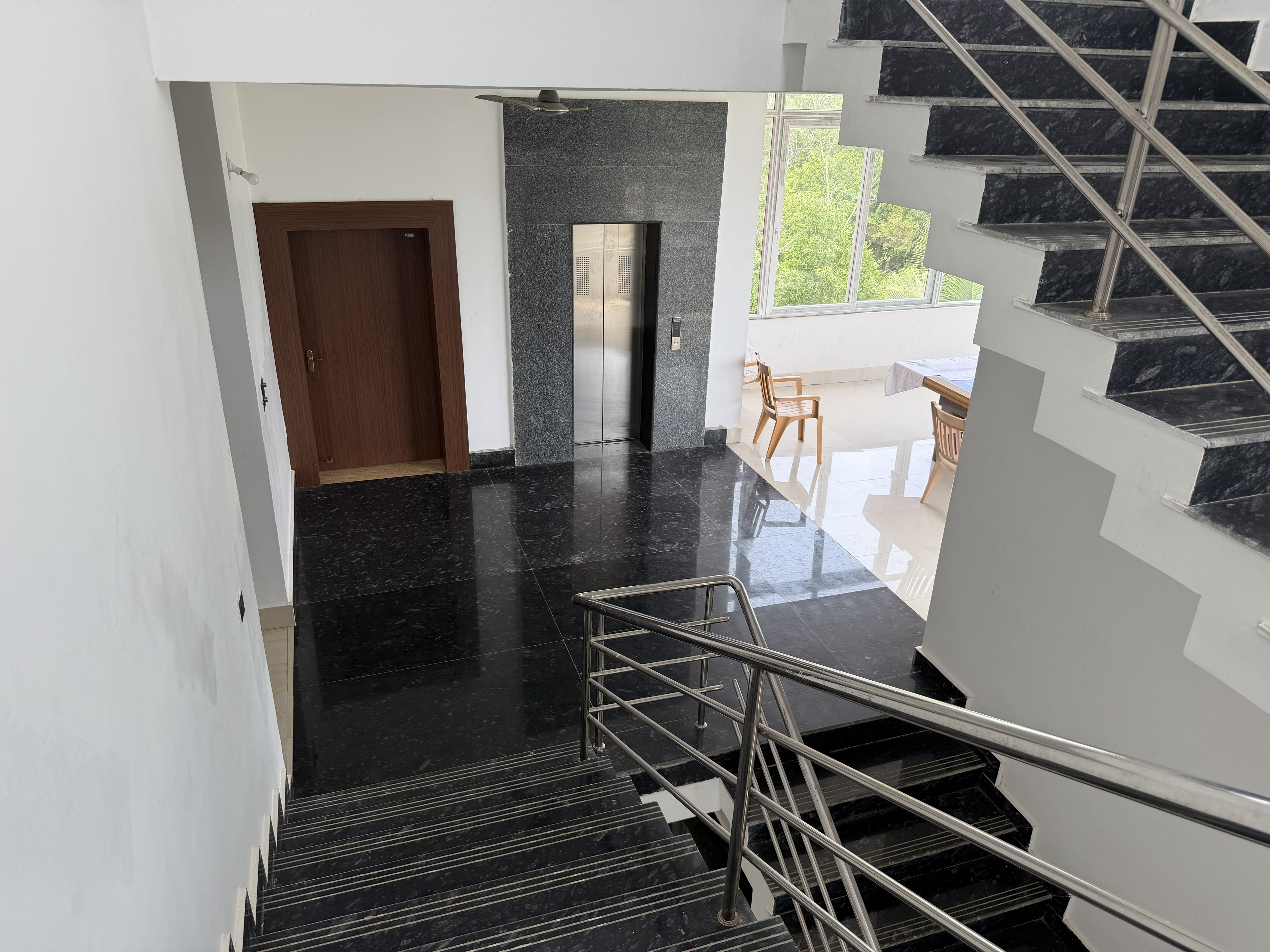 Un interior moderno con una escalera, una puerta y un ventanal.
