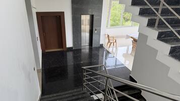 Un interior moderno con una escalera, una puerta y un ventanal.