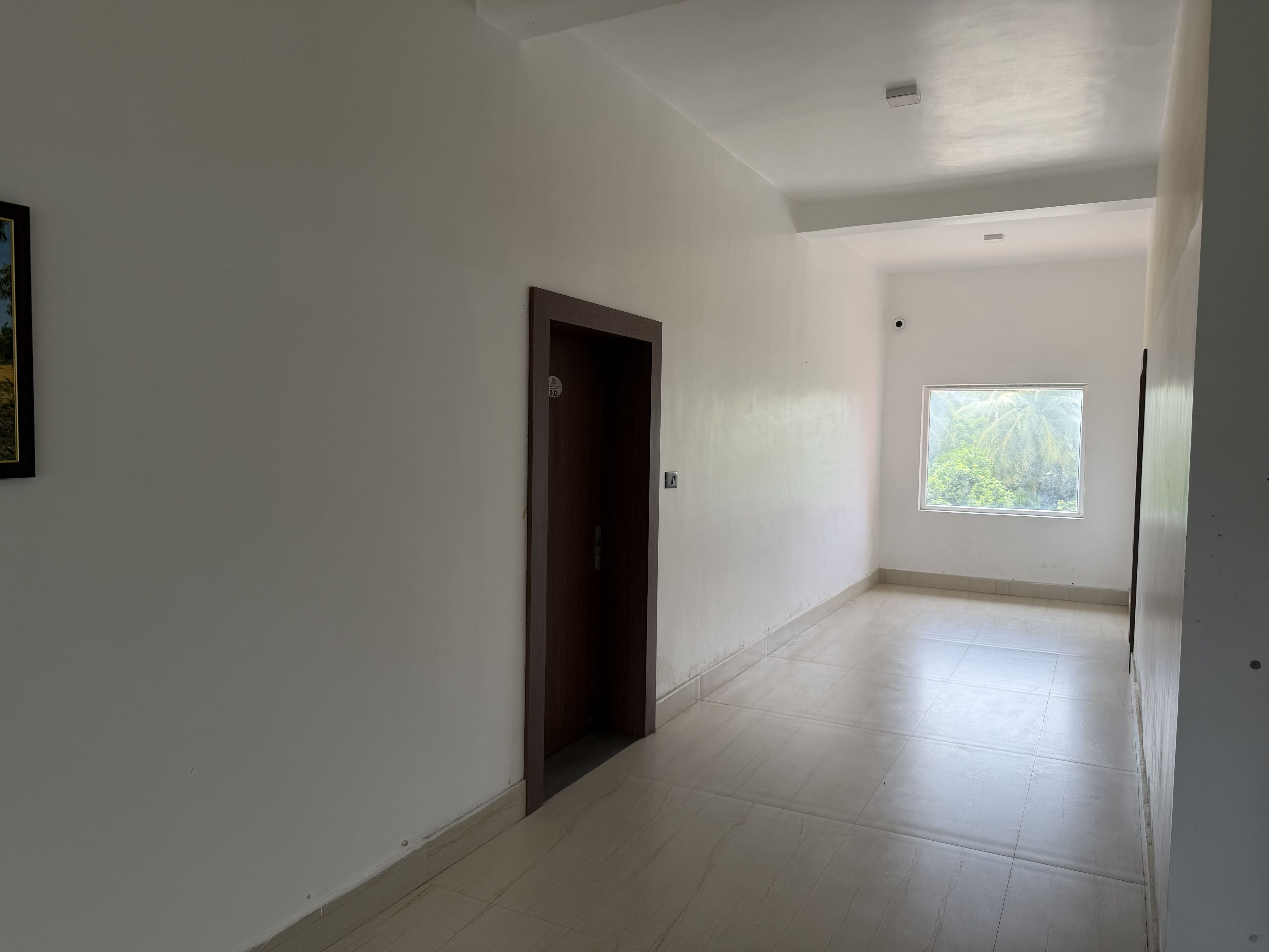 A hallway with a door, a window, and a tiled floor.